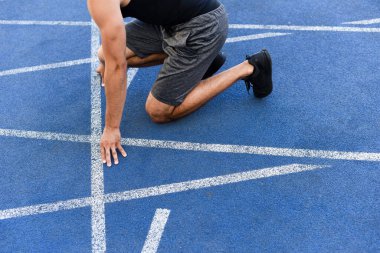 Stadyumdaki koşu pistinde koşucunun başlangıç konumundaki kırpılmış görüntüsü