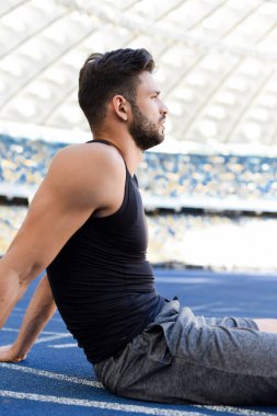 Stadyumdaki koşu pistinde başlangıç pozisyonunda yakışıklı koşucu