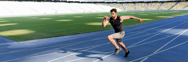 handsome runner exercising on running track at stadium, panoramic shot