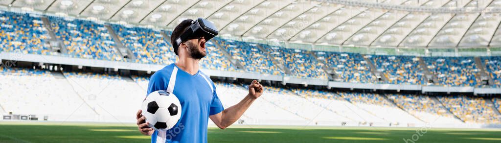 professional soccer player in vr headset with ball yelling and showing yes gesture at stadium, panoramic shot