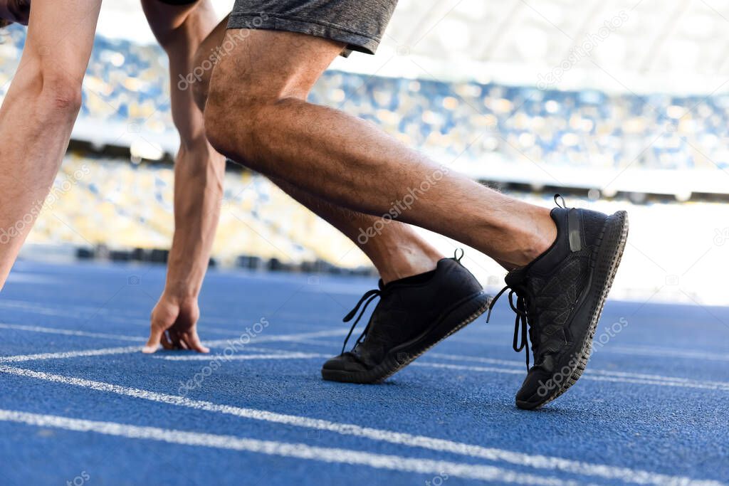 cropped view of runner in start position on running track at stadium