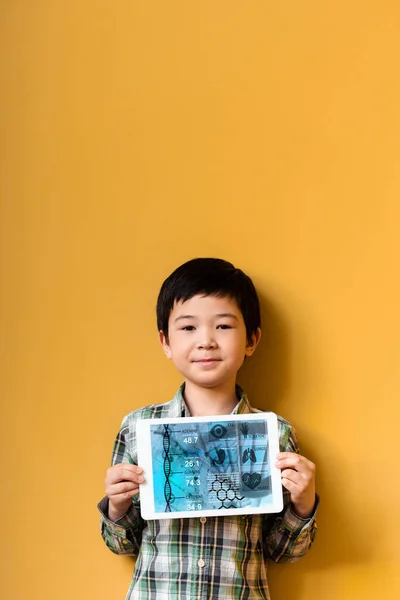 アジアの男の子は黄色の上に健康アプリとデジタルタブレットを保持 — ストック写真