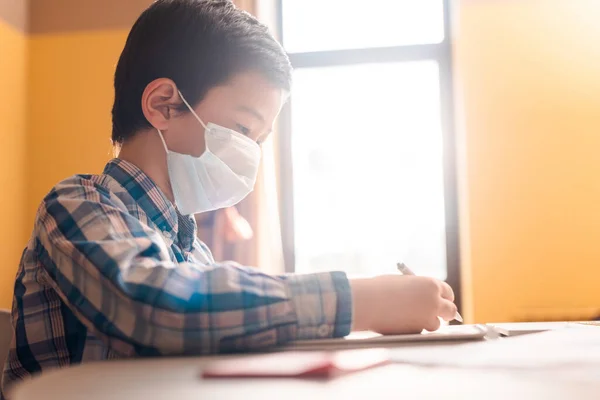 Azjatycki Chłopiec Masce Medycznej Pisanie Nauka Domu Światłem Słonecznym Podczas — Zdjęcie stockowe