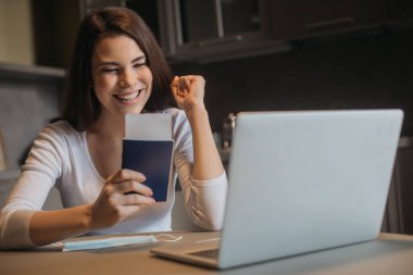 Laptop ve tıbbi maske yanında uçak bileti olan neşeli serbest çalışanların seçici odak noktası, karantina konseptinin sonu.