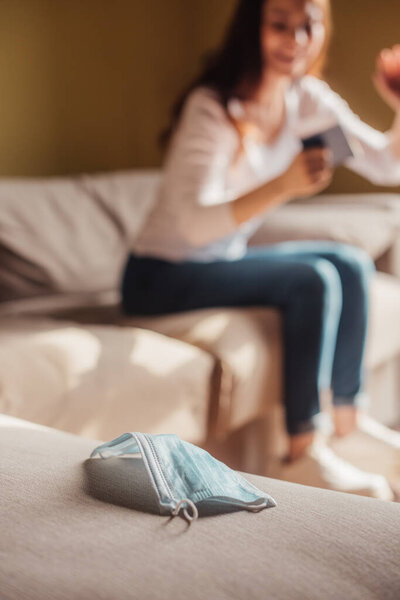 селективный фокус медицинской маски рядом с веселой девушкой, держащей паспорт с авиабилетом, конец карантинной концепции
