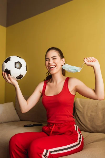 Cheerful Sportswoman Touching Medical Mask Holding Football End Quarantine Concept — Stock Photo, Image