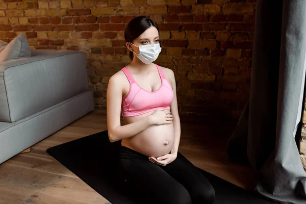 Ung Gravid Kvinne Sportstøy Medisinsk Maske Som Berører Magen – stockfoto