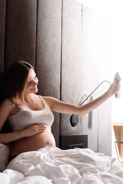 明るい妊娠中の女性がベッドルームで自撮り — ストック写真