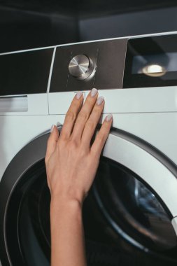 Çamaşır makinesinin kontrol paneline dokunan ev hanımı görüntüsü