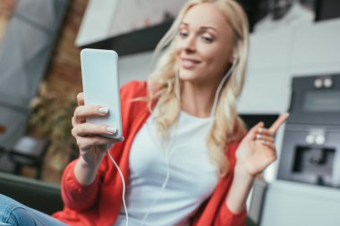 Kulaklıklı kadının akıllı telefona bakarken fikir jesti yaptığı seçici odak noktası