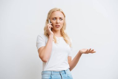Kafası karışık bir kadın omuz silkme hareketi yaparken beyaz telefondan izole edilmiş akıllı telefonu alıyor.