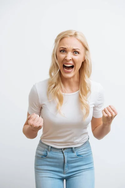 irritated woman screaming and showing fists while looking at camera isolated on white