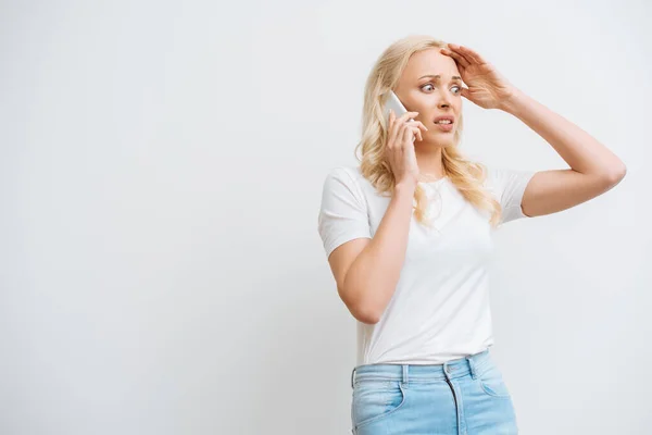 Mujer Conmocionada Tocando Cabeza Mientras Habla Teléfono Inteligente Aislado Blanco — Foto de Stock