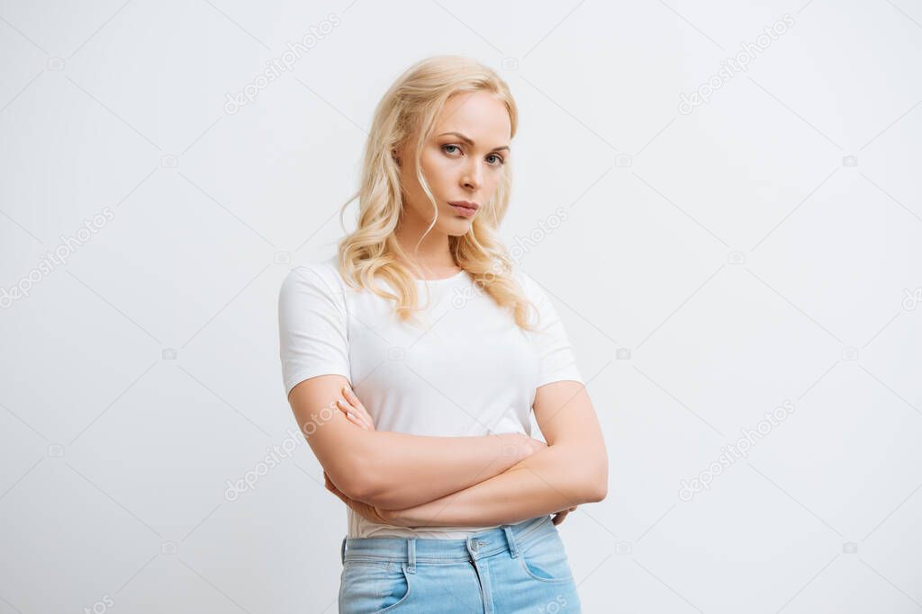 offended woman standing with crossed arms while looking at camera isolated on white