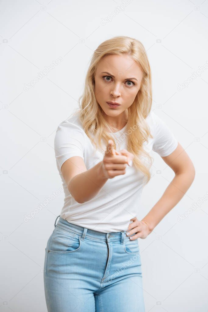 angry blonde girl pointing with finger at camera isolated on white