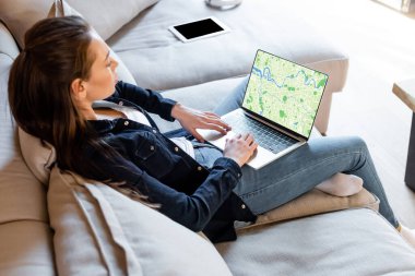 Boş ekranlı dijital tabletin yanında çevrimiçi haritalı dizüstü bilgisayar kullanan serbest çalışanın seçici odağı 