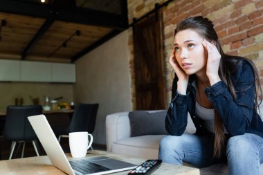 Laptop ve kupanın yanında film izlerken kafaya dokunan konsantre kızın seçici odağı 