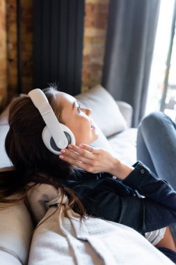 Müzik dinlerken kablosuz kulaklıklara dokunan neşeli kızın yan görüntüsü 