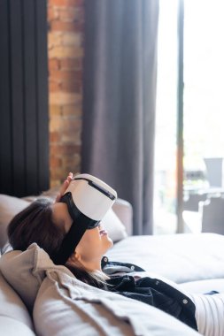 Sanal gerçeklikteki mutlu kızın koltukta uzanan kulaklığı.