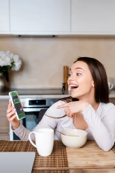 Chica Emocionada Apuntando Con Dedo Teléfono Inteligente Con Aplicación Reserva — Foto de Stock