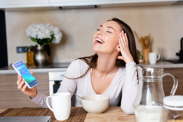 Cheerful Woman Holding Smartphone Booking App Laughing Breakfast — Stock Photo, Image
