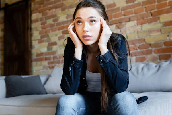 Konzentriertes Mädchen Berührt Kopf Während Auf Sofa Sitzt — Stockfoto