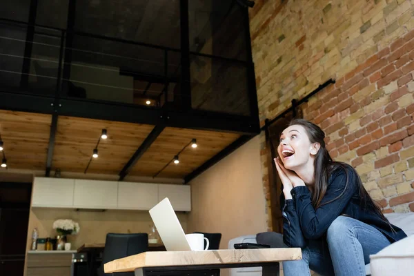 Chica Emocionada Sentado Sofá Viendo Película Cerca Computadora Portátil Taza —  Fotos de Stock