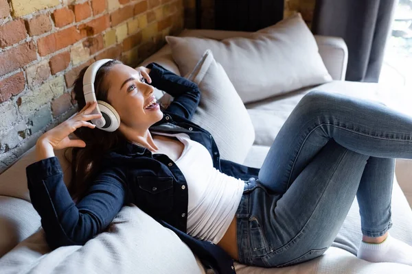 Alegre Chica Tocando Auriculares Inalámbricos Mientras Escucha Música — Foto de Stock