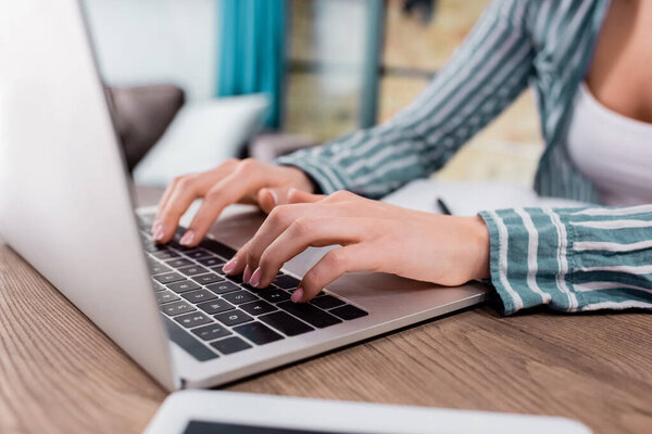 cropped view of freelancer typing on laptop keyboard 
