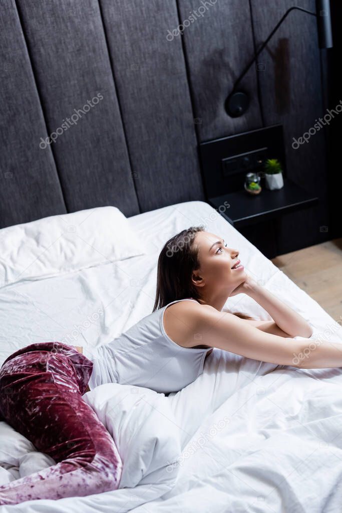 happy young woman lying on bed at home