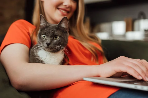 リビングルームで可愛い猫の近くのノートパソコンで幸せなフリーランサーの姿を切り取った — ストック写真