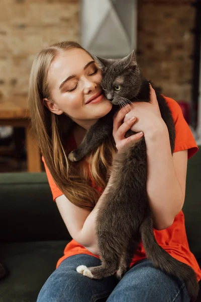 腕の中で目を閉じている陽気な女の子ふわふわ猫 — ストック写真
