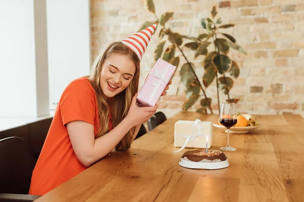 Fröhliches Mädchen Mit Geschenk Bei Einem Glas Rotwein Und Geburtstagstorte — Stockfoto