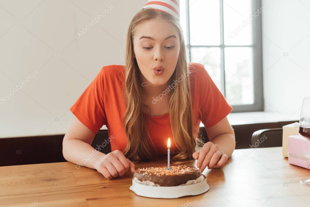 young woman blowing out candle on delicious birthday cake 