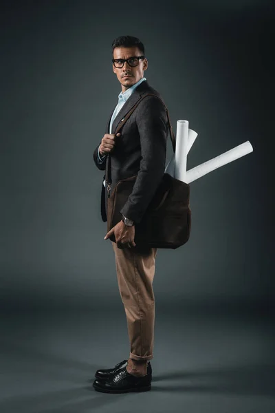 Businessman with blueprints in bag looking away — Stock Photo