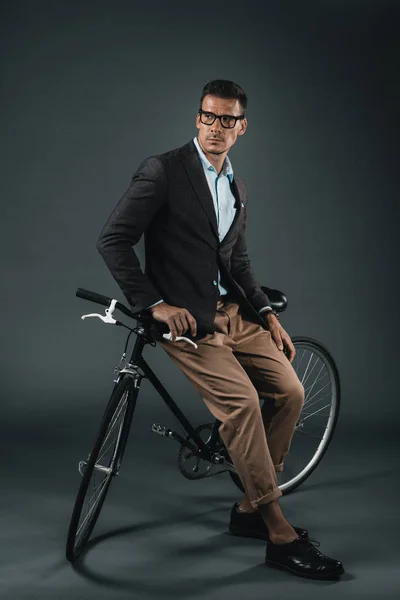 Joven hombre de negocios elegante sentado en bicicleta - foto de stock