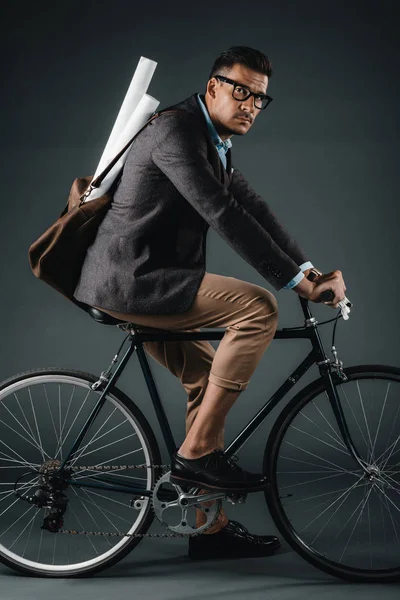 Young businessman with bag riding on bicycle — Stock Photo