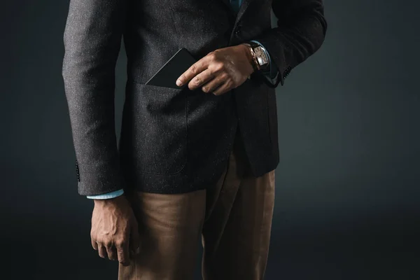 1 man putting smartphone in pocket of blazer — Stock Photo