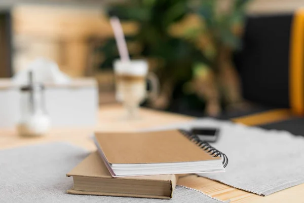 Livro e bloco de notas na mesa no café — Fotografia de Stock