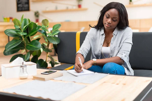 Mujer escribiendo en bloc de notas - foto de stock