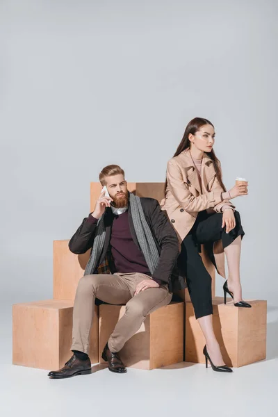 Pareja elegante con café para llevar y teléfono inteligente - foto de stock