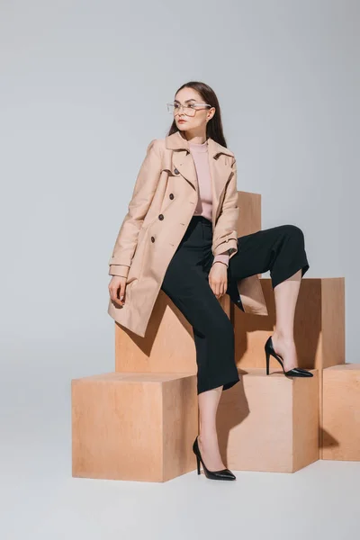 Fashionable woman sitting on wooden blocks — Stock Photo