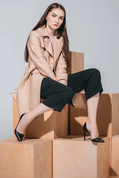 Fashionable woman sitting on wooden blocks — Stock Photo