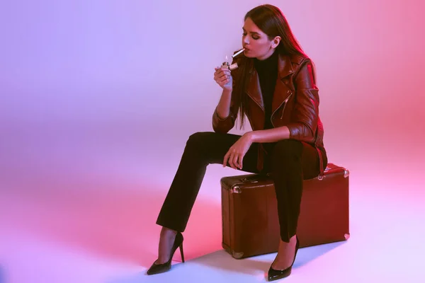 Курящая девушка сидит на чемодане — стоковое фото