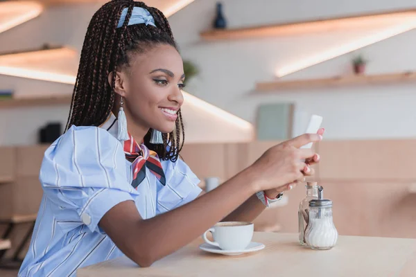 Femme afro-américaine utilisant un smartphone dans un café — Photo de stock