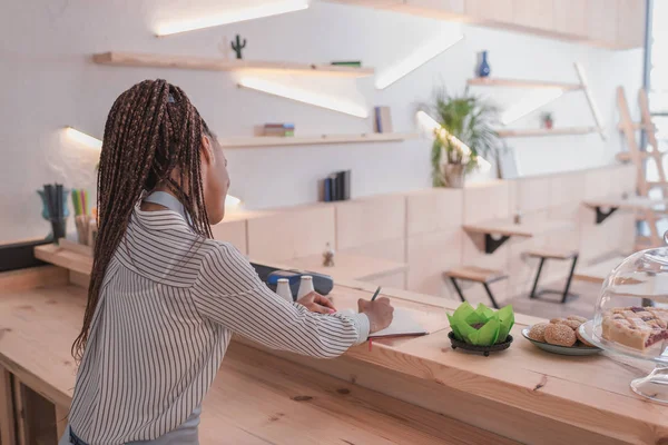 Barista writing in notebook — Stock Photo