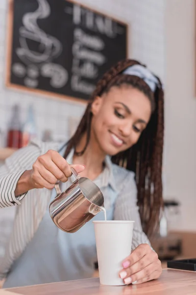 Barista pouring milk into coffee — Stock Photo