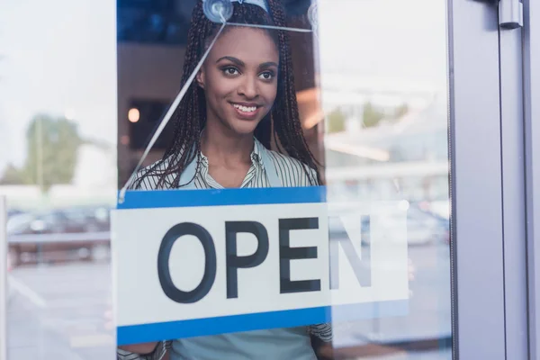 Empleado colgando cartel abierto en la puerta - foto de stock