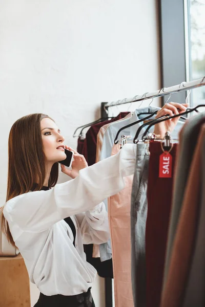 Donna con smartphone scegliere i vestiti — Foto stock