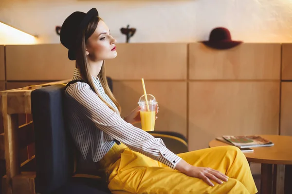 Chica con jugo sentado en la cafetería - foto de stock